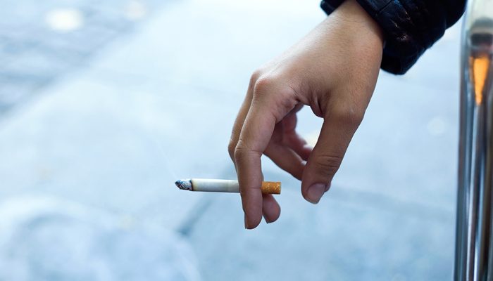 Close up of womans hand with cigarette in the street.