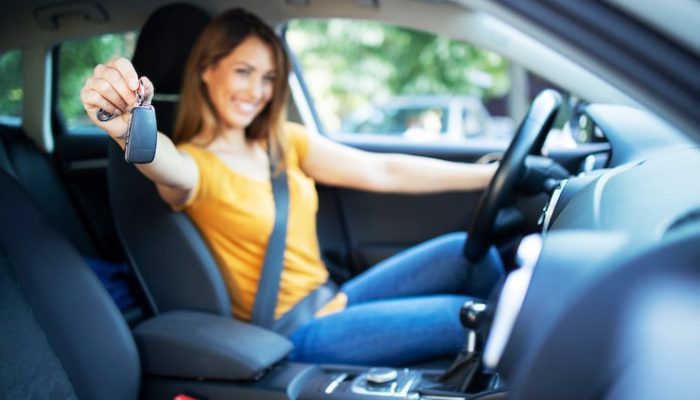 bela-mulher-motorista-sentada-em-seu-veiculo-e-segurando-as-chaves-do-carro-prontas-para-uma-viagem_342744-700
