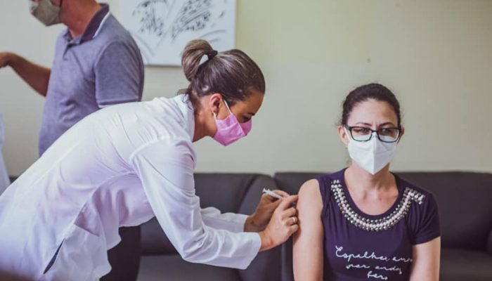 A foto mostra a enfermeira Raquel Alberto recebendo a primeira dose da vacina, no dia 20 de janeiro.
